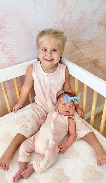 big sister holding little sister in matching spearmintlove rompers