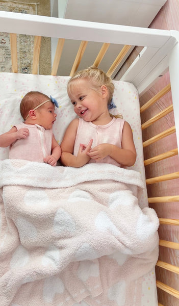 two children lying in crib looking at each other