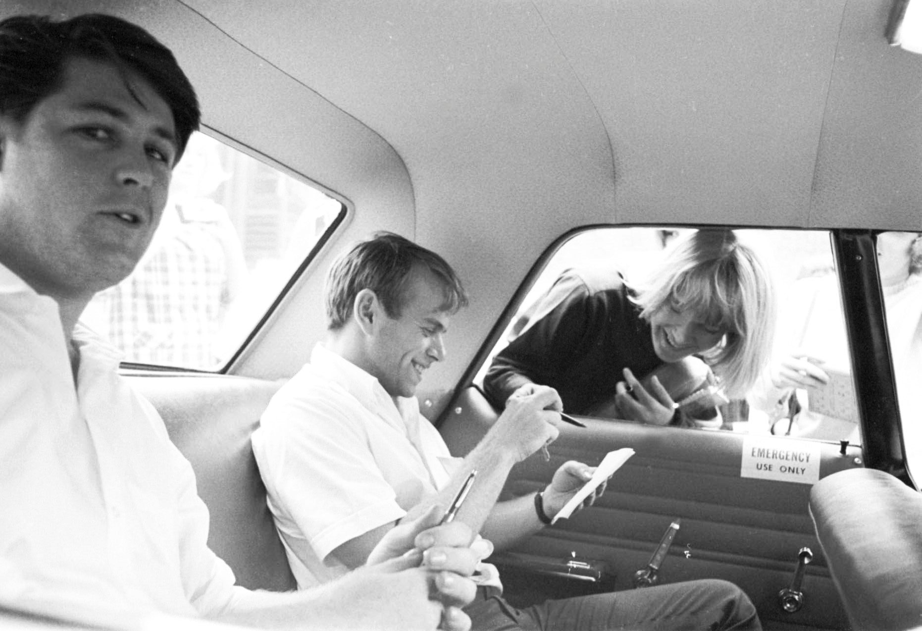 Brian Wilson and Al Jardine in a cab signing autographs