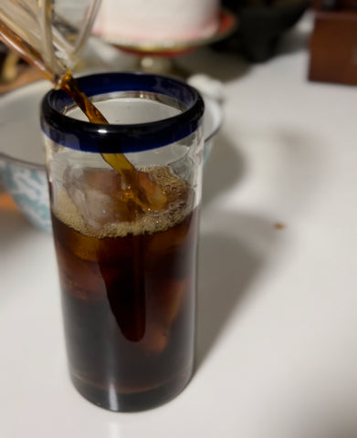 Pouring cold-brewed coffee into glass filled with ice