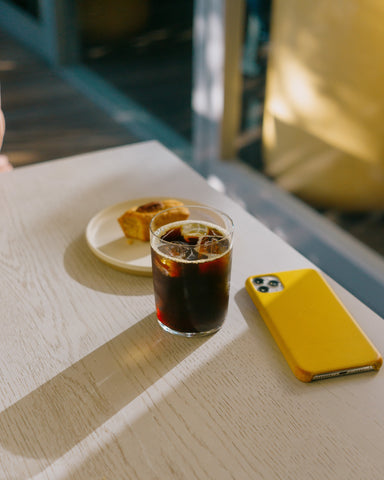 Table with iced coffee with cell phone facing down