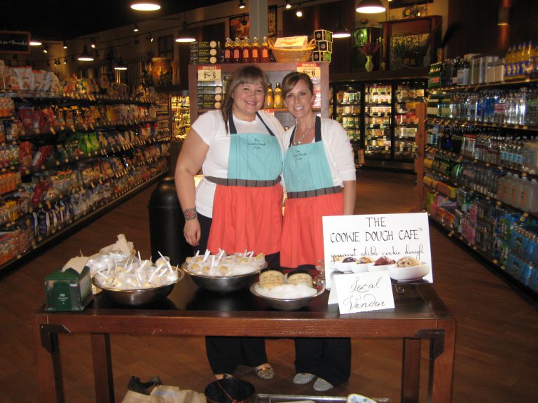 Joan and Julia standing behind a sample table at The Fresh Market