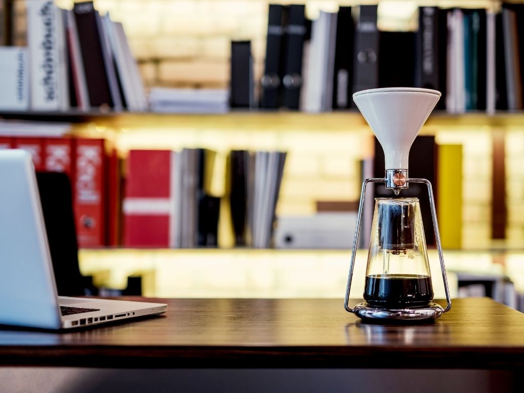 Gina Smart Coffee Maker Brewing coffee in a Gina Smart White in a desktop next to a laptop