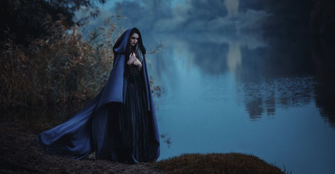 Witchy vibe female with a cloak standing by element water 