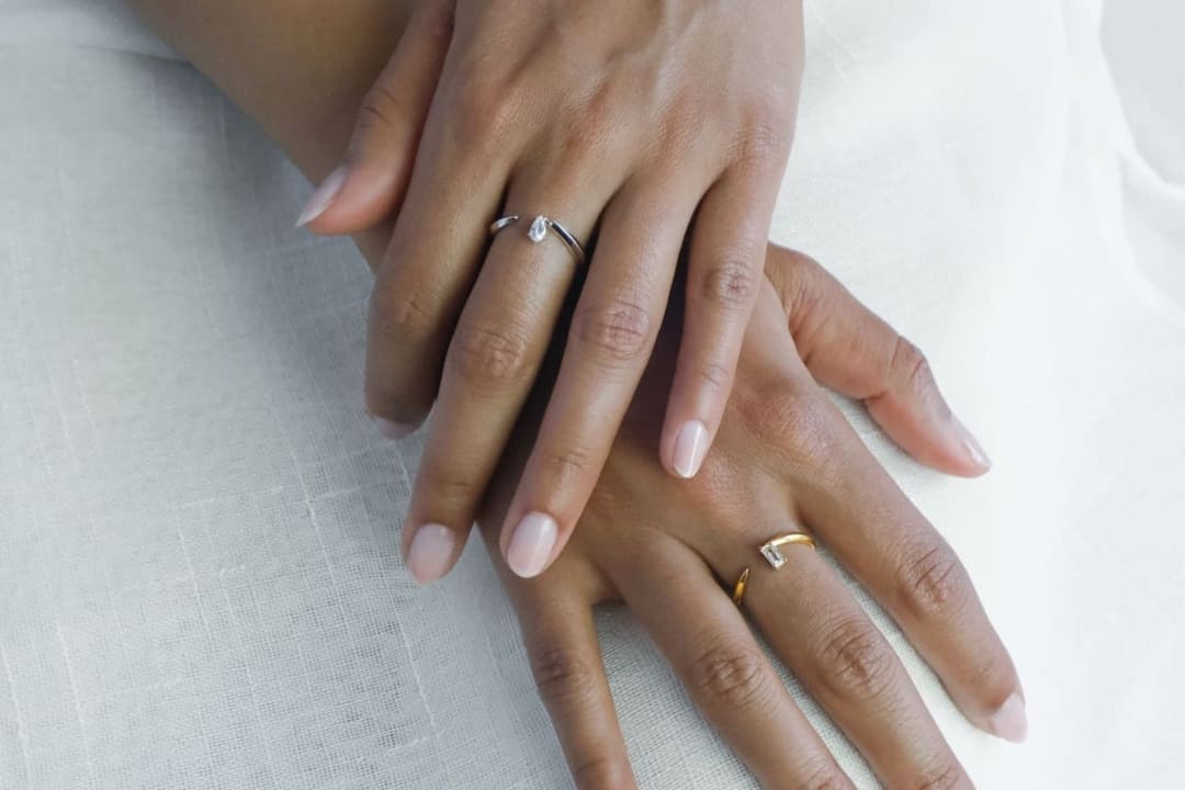 Open cuff ring on model's hands, featuring small white topaz gemstones