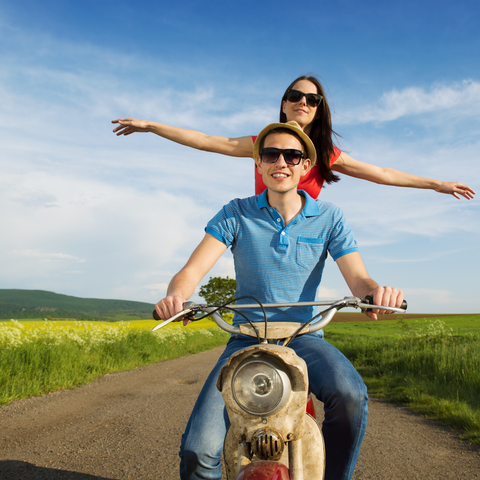 Man and woman on motor bike enjoy the ride green Summer background 