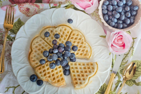 Plate of heart shaped waffles with blueberries on a floral tablecloth