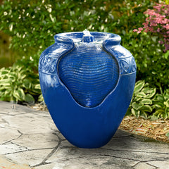 A blue glazed pot water fountain sitting on some garden stones.