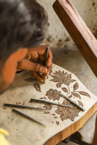 Hand carving intricate motifs on wooden blocks 