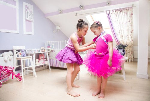 One girl helps the other dress up as a princess