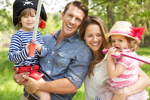 Mom and Dad holding kids wearing dressup costumes.