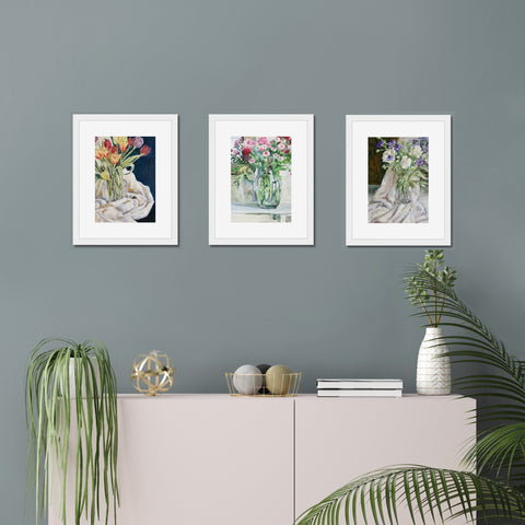 Three giclee art prints of oil paintings of tulips, nigella, peonies and pink flowes in vases, framed and hung on a wall