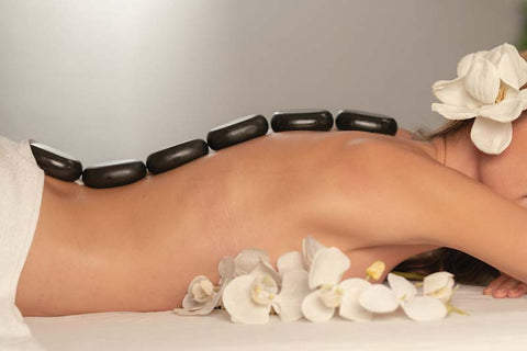 woman's bare back laying down with hot stones along the spine