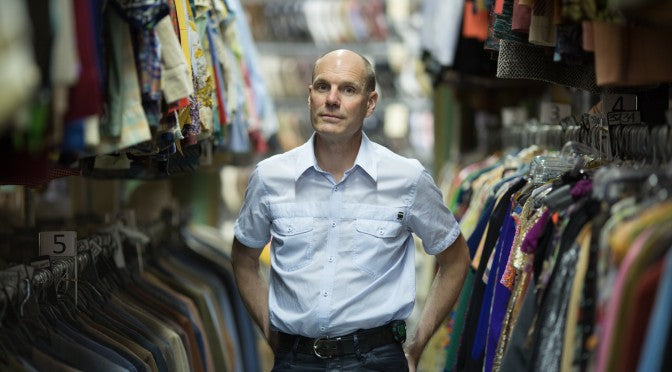 Portrait of Ian in a studio aisle surrounded by clothing racks