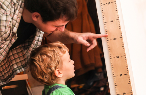 ID: Father and son looking at height ruler