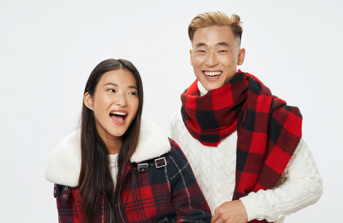 Man and woman wearing matching red and black tartan themed scarf and jacket
