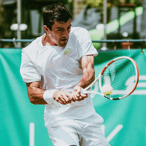 image of male tennis player hitting tennis ball wearing lotto
