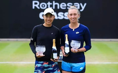 Shuai Zhang and Elise Mertens holding trophies and champagne 