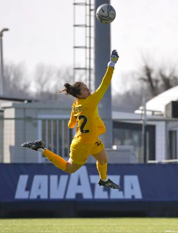 female soccer player hitting away a soccer ball in goal 