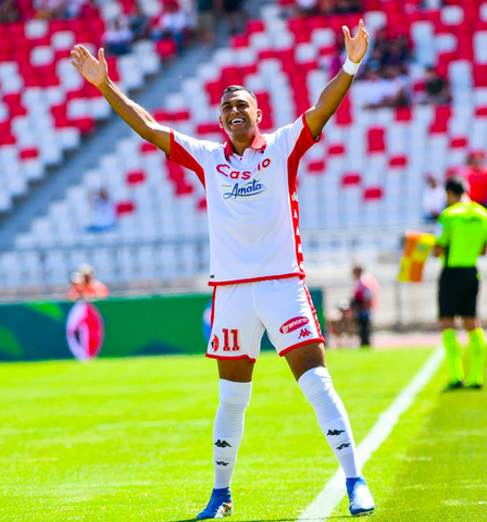 Walid Cheddira standing on soccer field holding arms up 