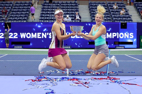 Czech stars Katerina Siniakova and Barbora Krejcikova jumping in the air holding trophy 