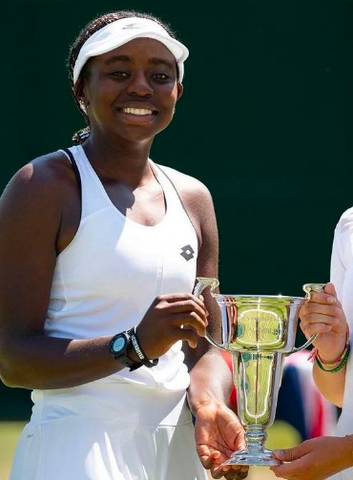 Angella Okutoyi holding trophy for winning Girls’ Doubles at Wimbeldon. 