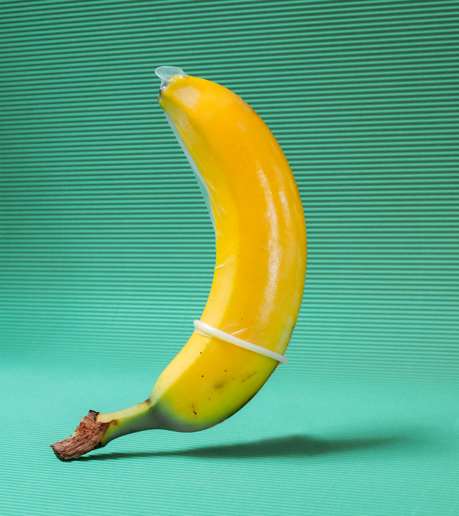 Eine Banane mit einem Kondom symbolisiert die Bedeutung von Sicherheit und Verantwortung bei der Verwendung von CBD-Ölen zur Steigerung der Intimität.