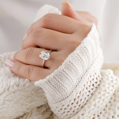A beautiful oval engagement ring with white gold band on woman in white sweater's hand