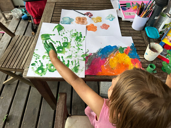 A little girl painting a colourful drawing with paints. 