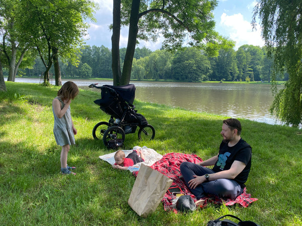 Family with young children having a picnic on the banks of a pond