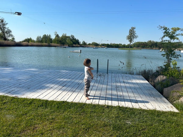 Little girl standing on the bank of a pond.
