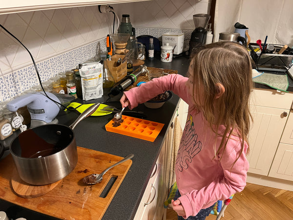 Little girl in a pink blouse preparing home made chocolates. 