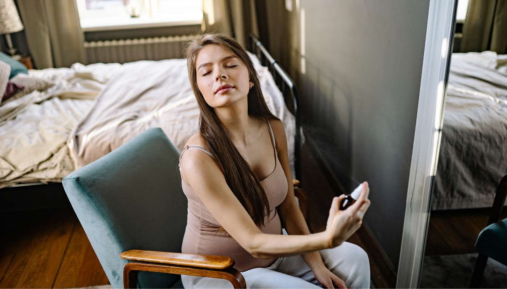 Pregnant woman spraying perfume