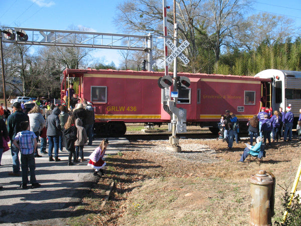 Full shot of caboose of the Santa Express in 2019 with crowd lined up waiting to the left and volunteers to the right.