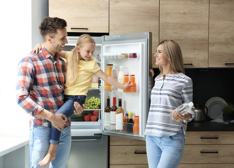 A happy family with the energy saving refrigerator at the background