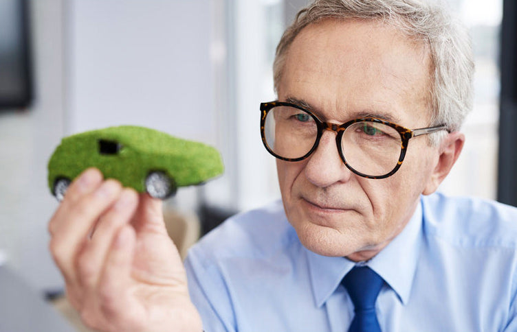 A old man holding a conceptual green car model