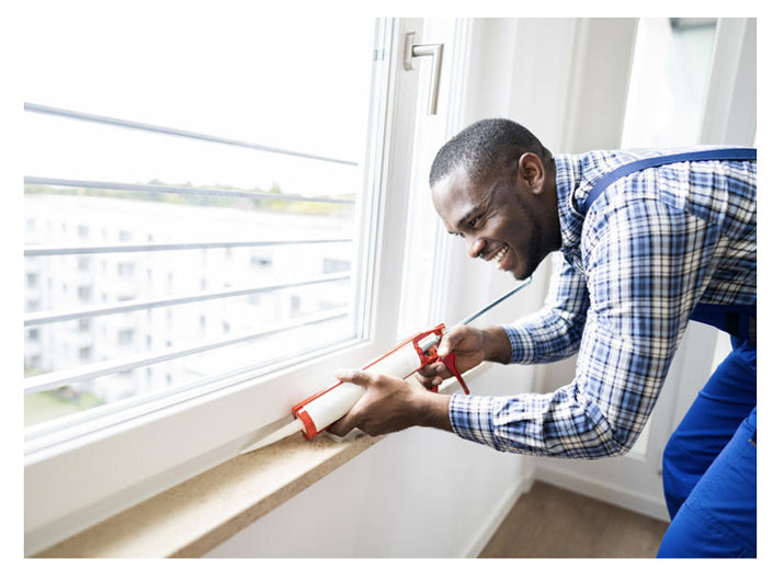 A worker putting the waterproof sealant on the window