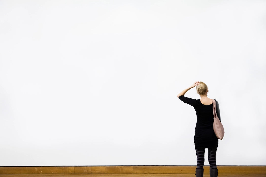 Femme interrogative face à un mur vierge