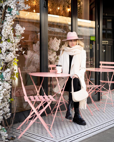 girl wearing pink fedora hat with croc curved shoulder bag at pink cafe 
