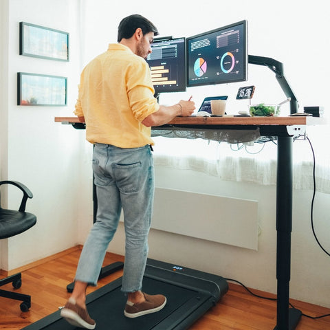 man working on a treadmill operating under a standing desk