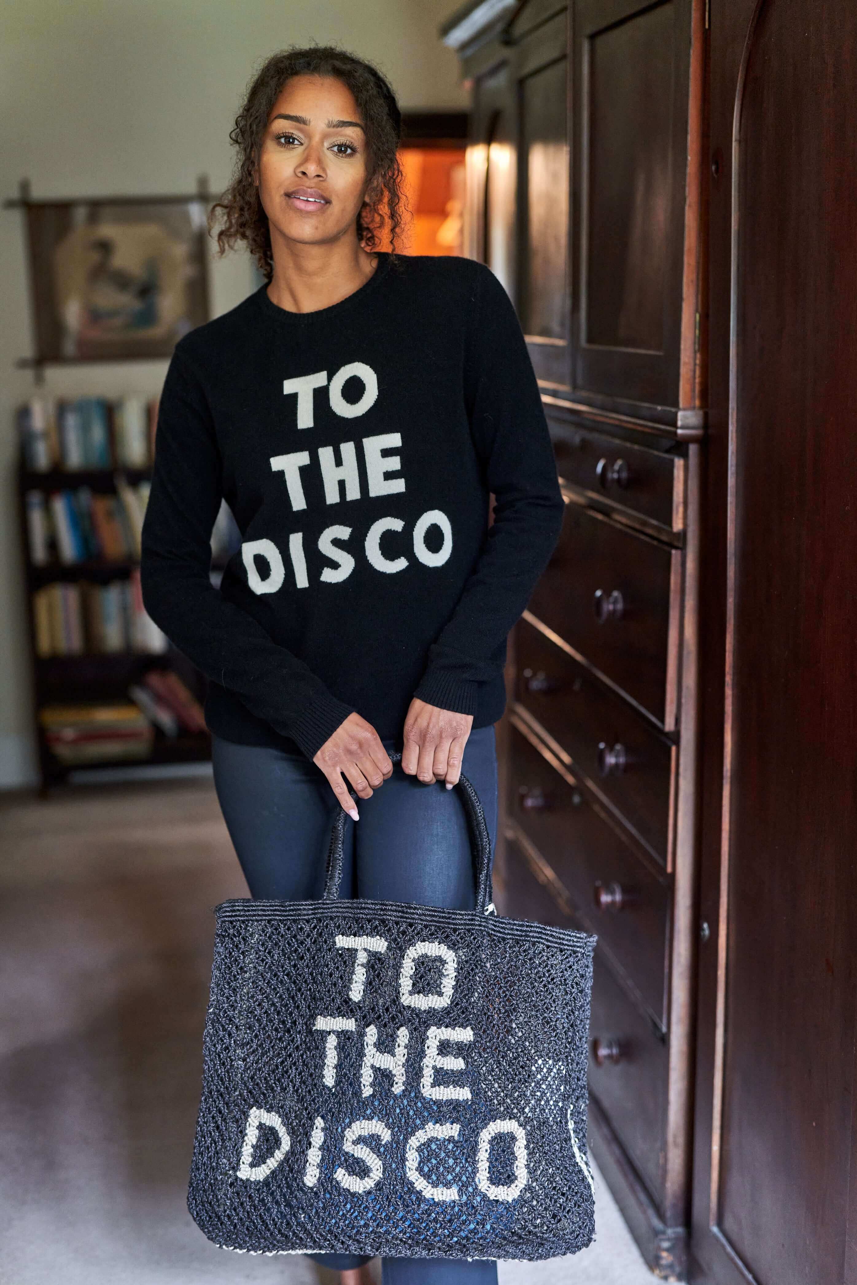 Model wearing black "To the Disco" cashmere crew neck holding "To the Disco" matching tote bag Jumper 1234 x The Jacksons collaboration 