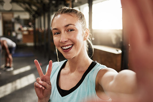 woman smiling at the gym as she takes a selfie