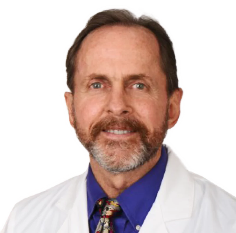 Portrait of a smiling man with a beard wearing a lab coat and a tie.