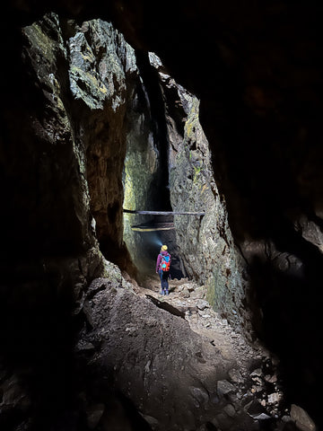 A woman stands lighting up a mine tunnel with a headtorch