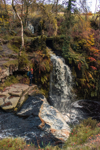 Woman looks down into Lumb Hole Waterfall