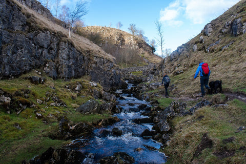 A man and woman walk next to a river