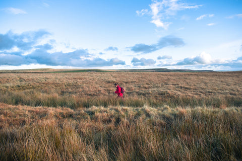 Woman walks across moorland in Yorkshire near Hardcastle Crags