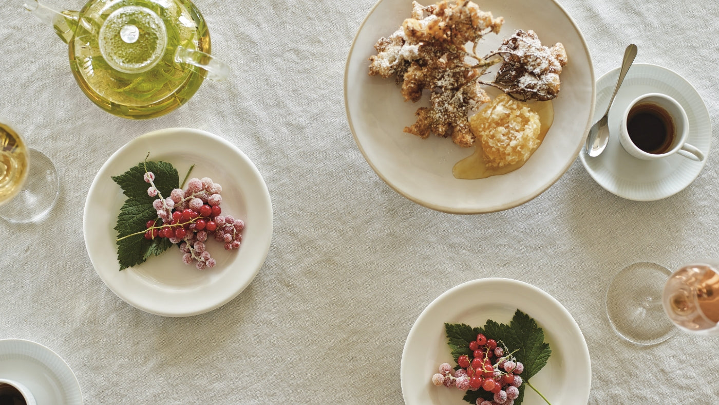 plates with berries and pastries on white tablecloth