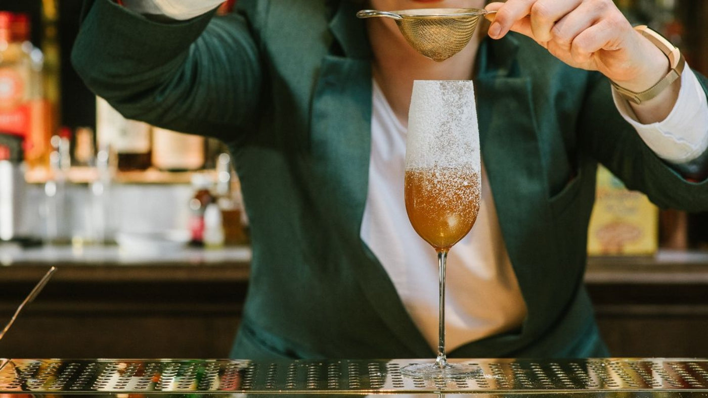 bartender straining cocktail into champagne flute