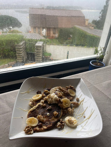 Plate of banana pancakes topped with bananas, walnuts, yogurt & honey